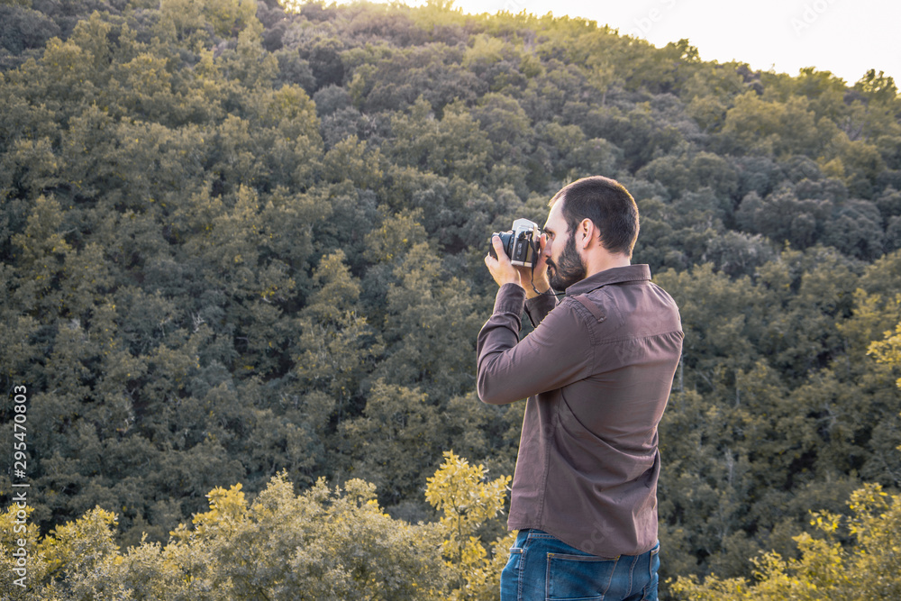 young man taking photos to landscape with analog camera