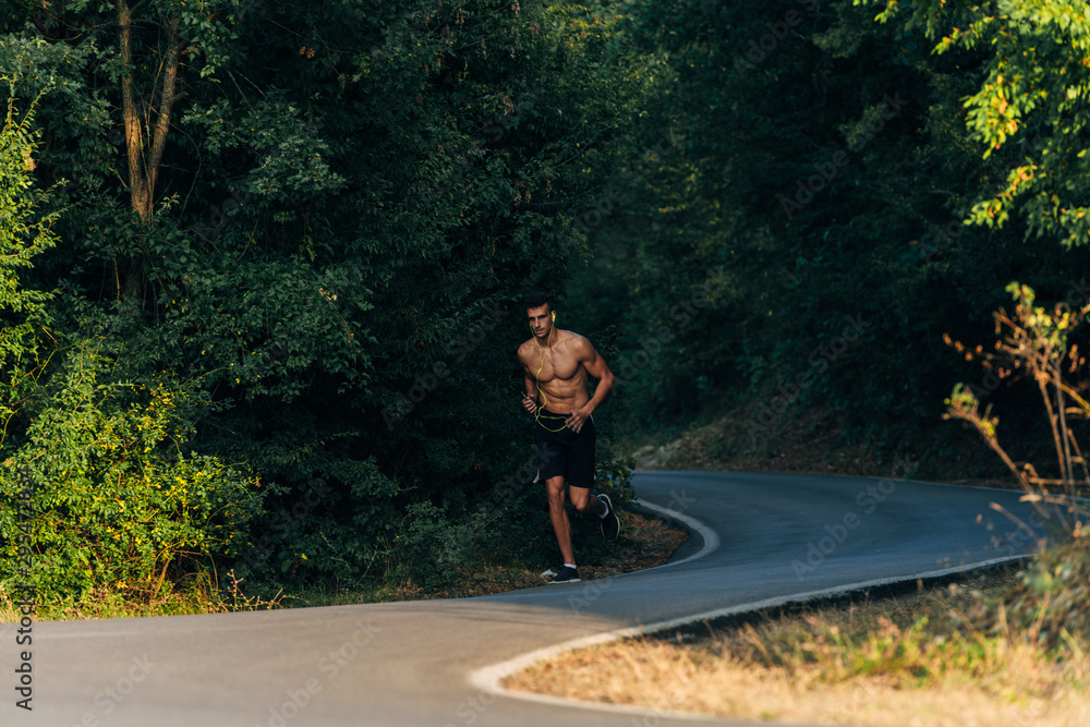 Full body portrait of a fit man running outdoors through mountain Full body portrait of a fit man running outdoors through mountain