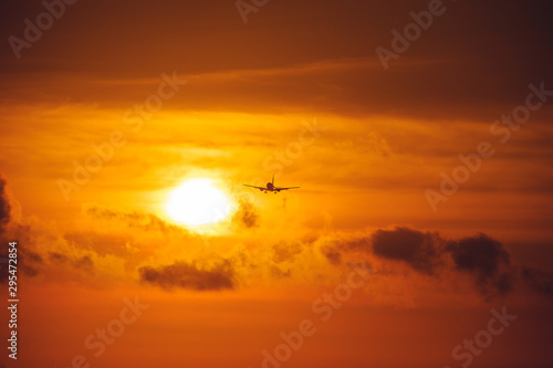 Silhouette of a passenger airliner in the sky during sunset. Airplane in the sky. © Evgenii Starkov