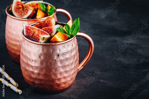 Photography Fig moscow mule ice cold cocktail in copper cup with oranges and mint