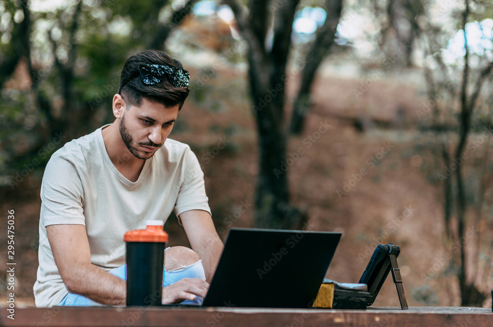 Freelancer man with notebook sitting on the park bench Freelancer man with notebook sitting on the park bench