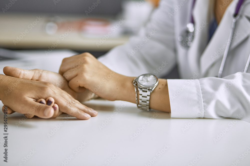 Woman doctor calms patient and holds hand