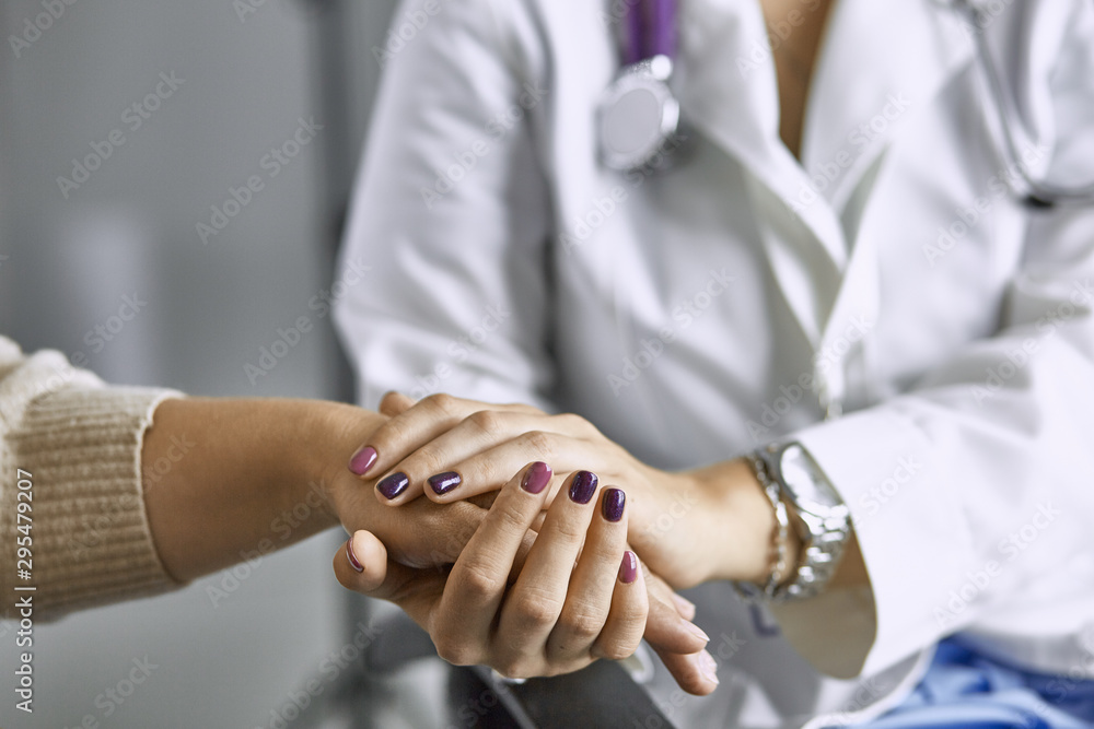 Obraz premium Woman doctor calms patient and holds hand