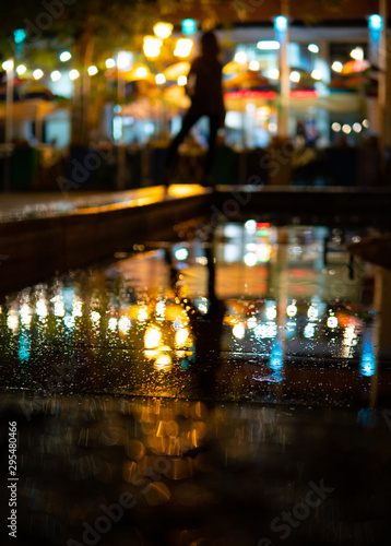 Bokeh backlight girl silhouette after rain on the street at night