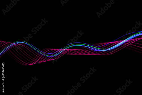 Long exposure photograph of neon pink and blue colour in an abstract swirl, parallel lines pattern against a black background. Light painting photography.