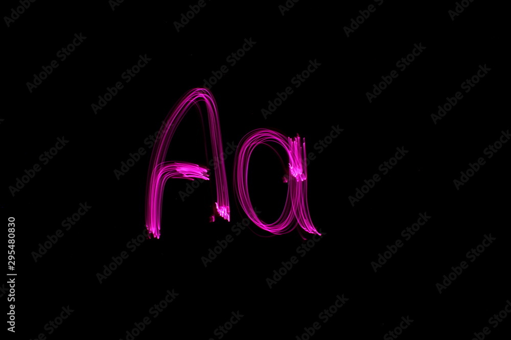 Long exposure photograph of the letter A in pink neon colour in an abstract swirl, parallel lines pattern against a black background. Light painting photography. Long exposure photograph of the letter A in pink neon colour in an abstract swirl, parallel lines pattern against a black background. Light painting photography.