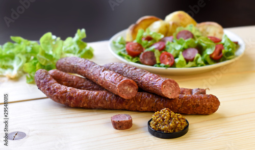 Smoked sausage with vegetables salad on a wooden board