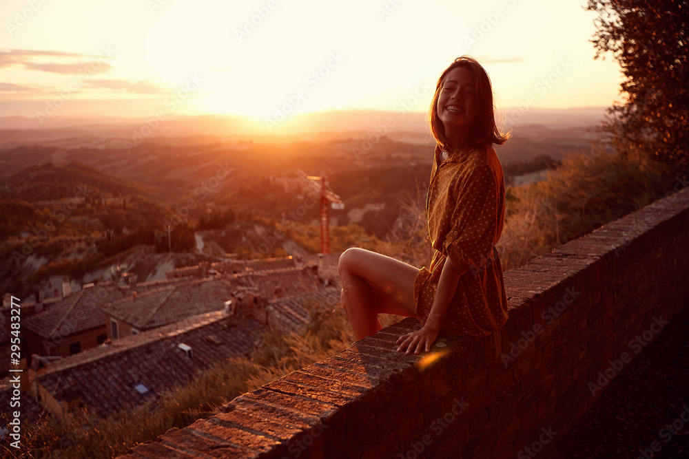 woman at sunset. Smiling woman is enjoying sunset - obrazy, fototapety, plakaty 