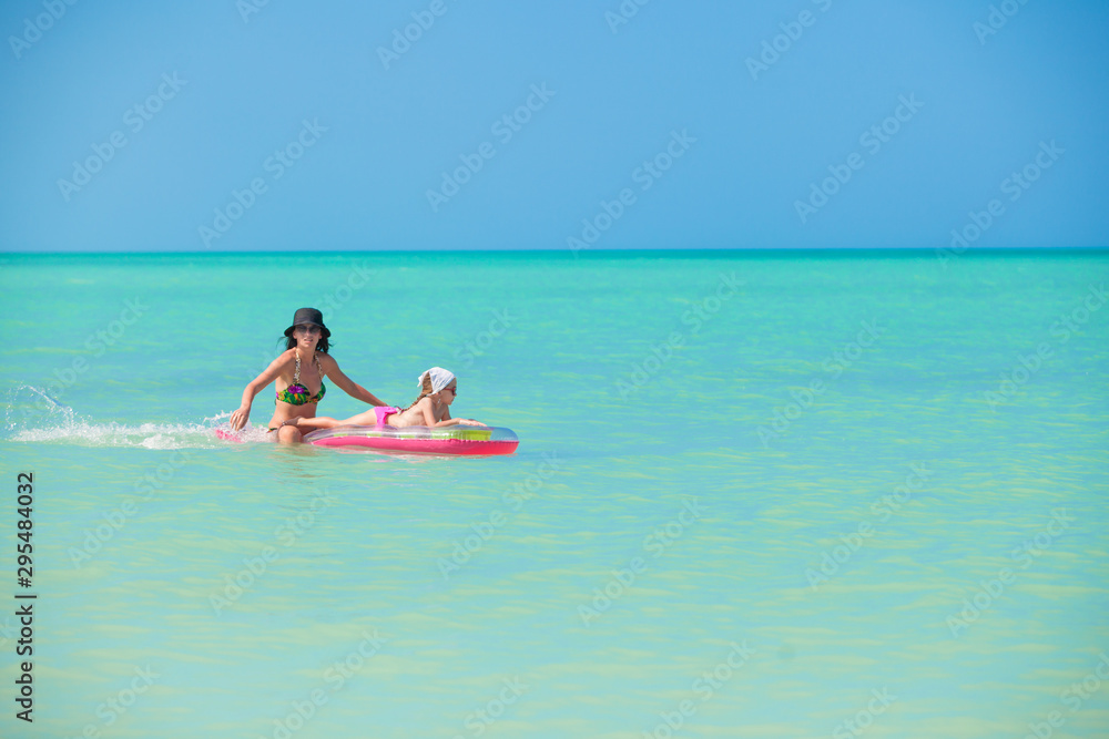 Fototapeta premium Mother with young daughter on an air mattress in the sea