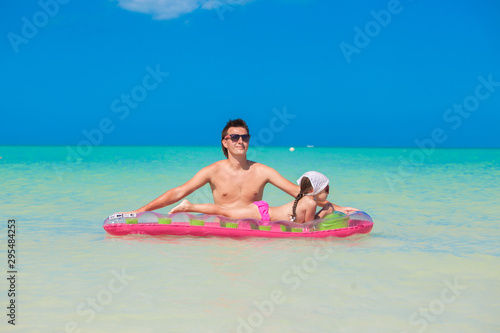 Young father with cute daughter on an air mattress in the sea © travnikovstudio