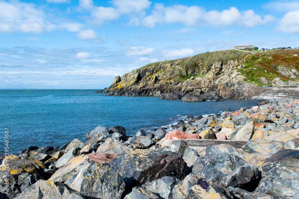 Cliffs and view of Irish Sea at sunny day in Portpatrick in Scotland. Scenic view of ocean and cliffs in Dumfries and Galloway. Beautiful seaside in Scotland. Blue sky. Sunny day.