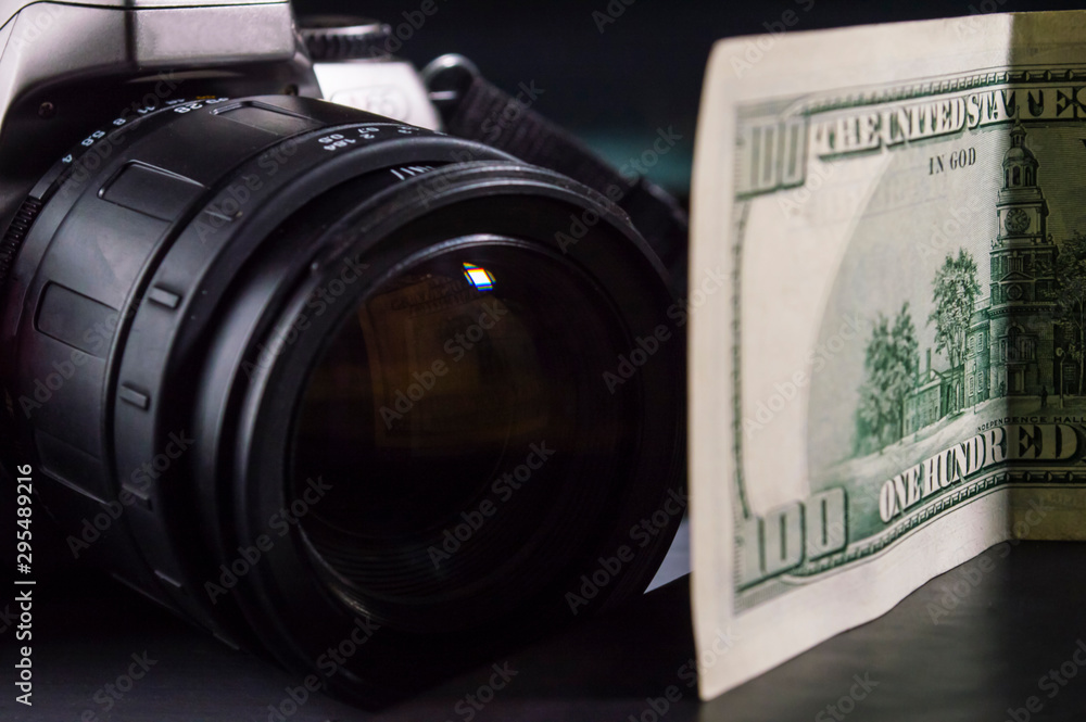 Closeup of  camera lens and  hundred dollar bill