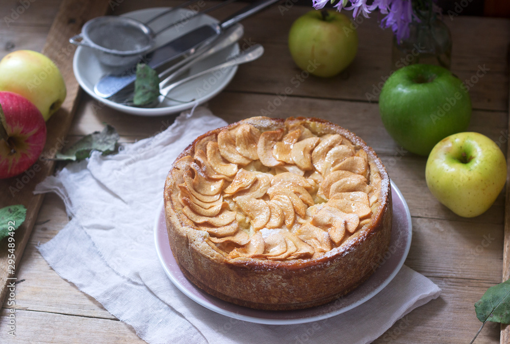 Pie with apple cream filling, apples and dishes on a wooden background. Rustic style. Pie with apple cream filling, apples and dishes on a wooden background. Rustic style.