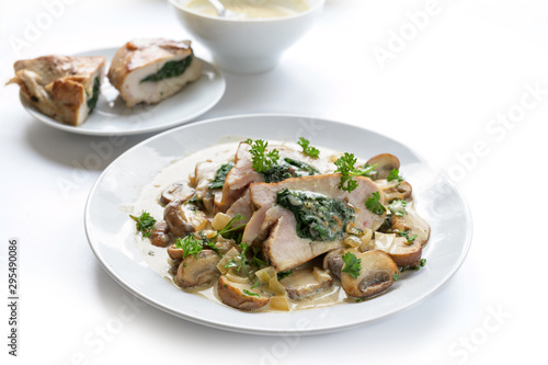 chicken breast fillet stuffed with spinach filling, served with mushrooms, parsley garnish and a creamy gorgonzola sauce, white background with copy space