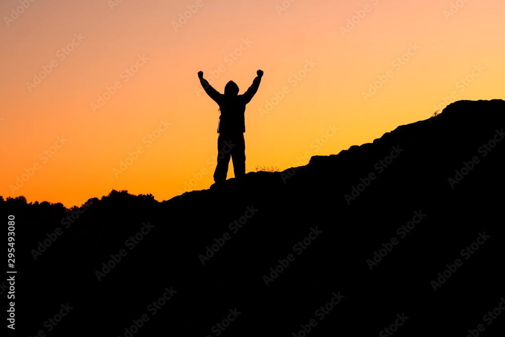 a photograph of a man standing on the mountains holding his hands up