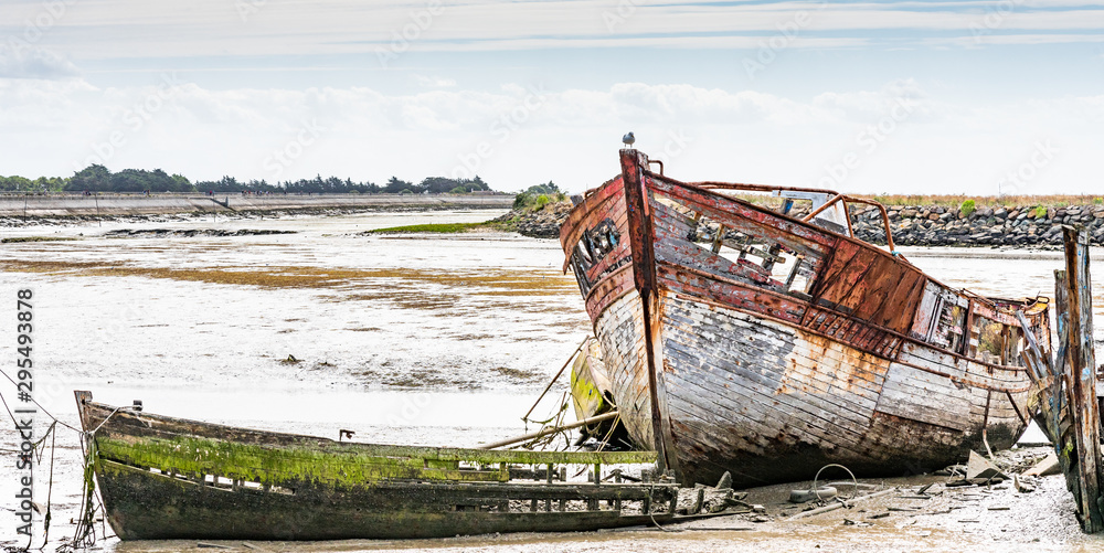 The Noirmoutier boats cemetery. A group of wrecks of old wooden fishing boats are piled on the mud.