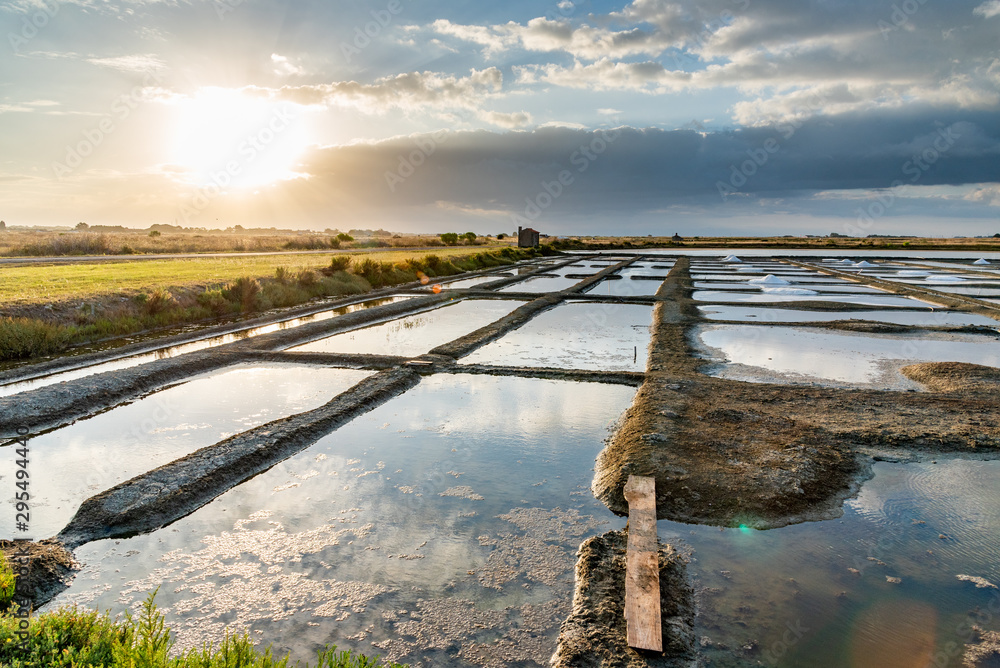 Salt marshes on the island of Noirmoutier in France..The sun rises on ponds, basins and .salt piles
