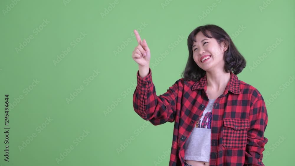 Happy Asian hipster woman thinking while pointing up Happy Asian hipster woman thinking while pointing up