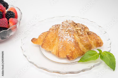 Croissant on a plate with a bowl of berries