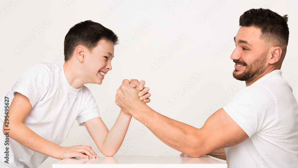 Playful dad and son compete in arm wrestling Playful dad and son compete in arm wrestling