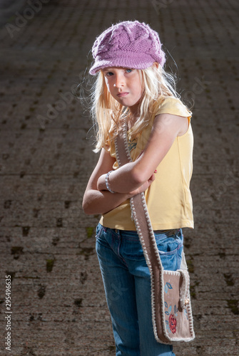 Pretty young blonde hippie girl in pink hat and brown bag with dramatic lighting