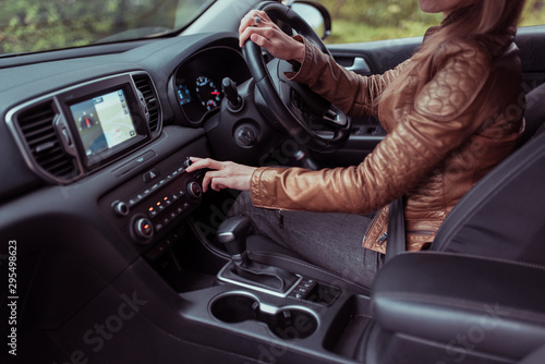 woman driving car, summer autumn forest, turns volume on off radio, increases adjustment air conditioner, activates button. Automatic transmission. Right-hand drive left-hand. Steering wheel right.