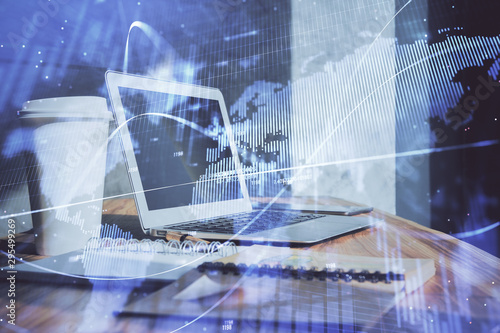 Stock market graph on background with desk and personal computer. Double exposure. Concept of financial analysis.