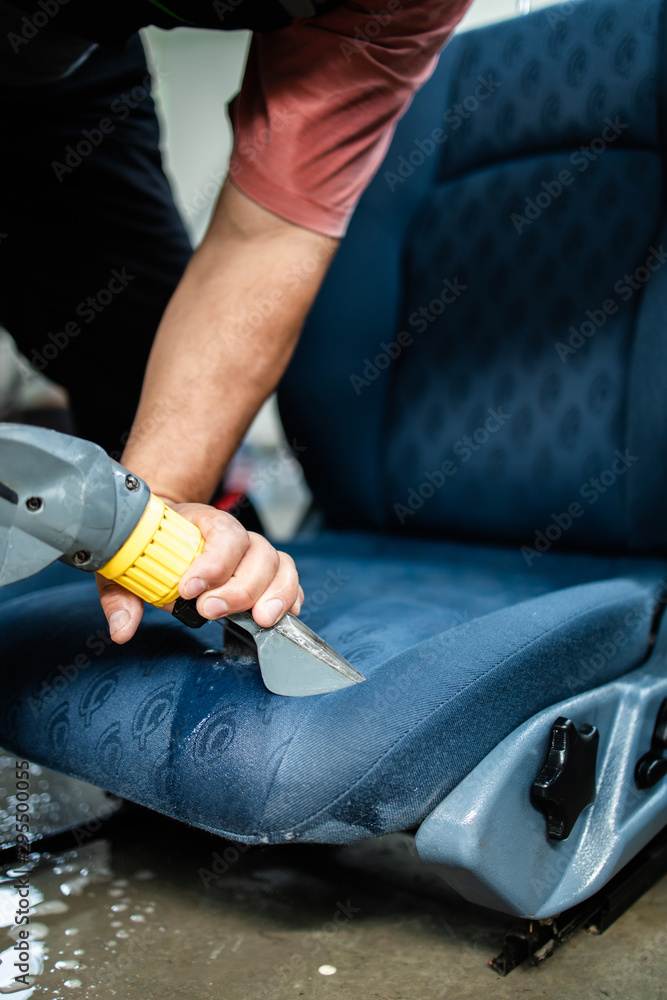 Car wash service worker wet cleaning vehicle interior and seats