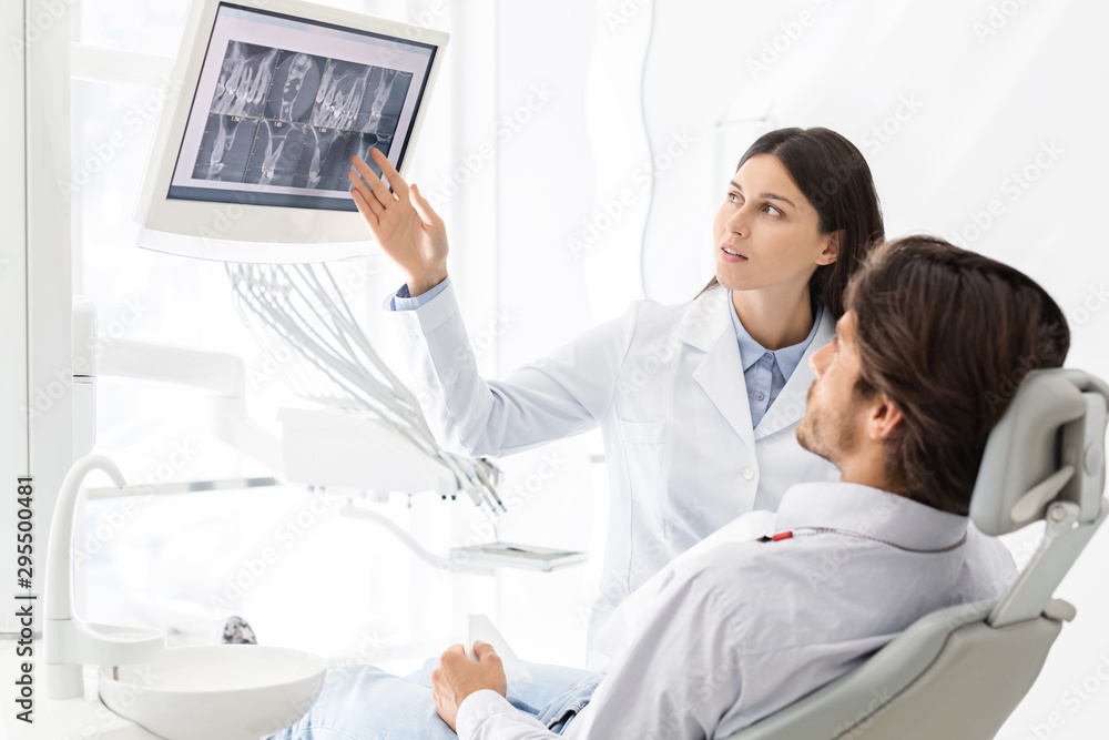 Obraz premium Pretty dentist doctor demonstrating his patient x-ray results