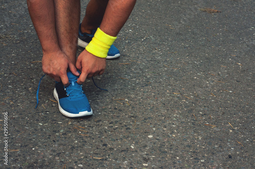 Young tanned male runner tying shoelaces, getting ready for a run. The concept of a healthy lifestyle, freedom