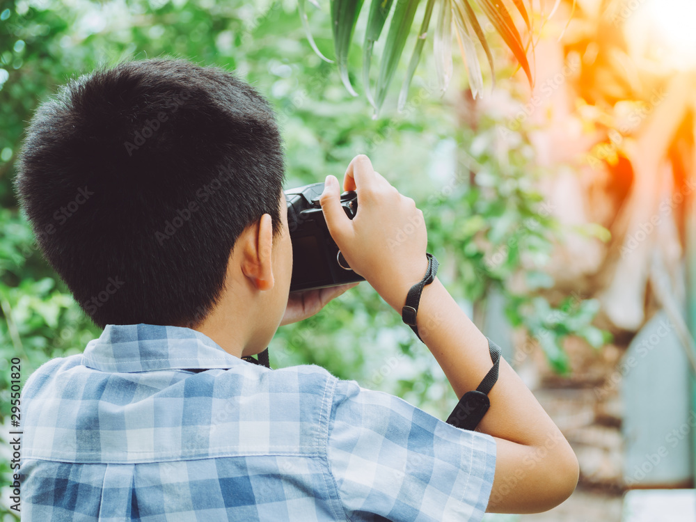 Young asian boy looking for attractive and taking photo by camera on forest background and nature holiday. Travel concept Young asian boy looking for attractive and taking photo by camera on forest background and nature holiday. Travel concept