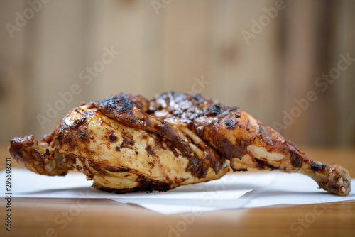 Half a grilled jerk chicken on table with copy space