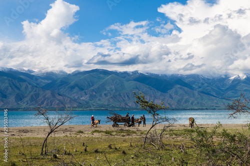 Issyk kul lake with children and wagon silhouette and mountains on background