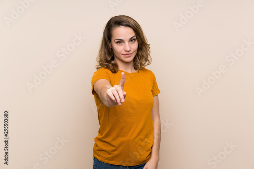 Young blonde girl over isolated background showing and lifting a finger