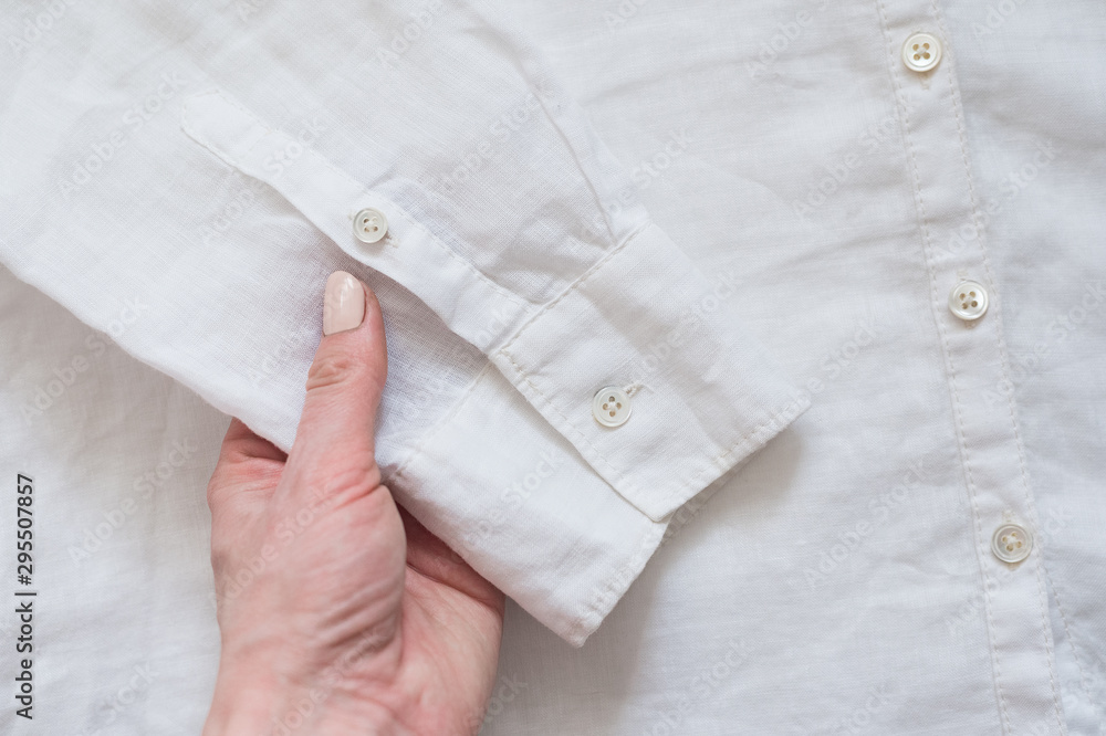 Sleeve of white shirt in female hand. Clothes concept. Details of clothes Sleeve of white shirt in female hand. Clothes concept. Details of clothes