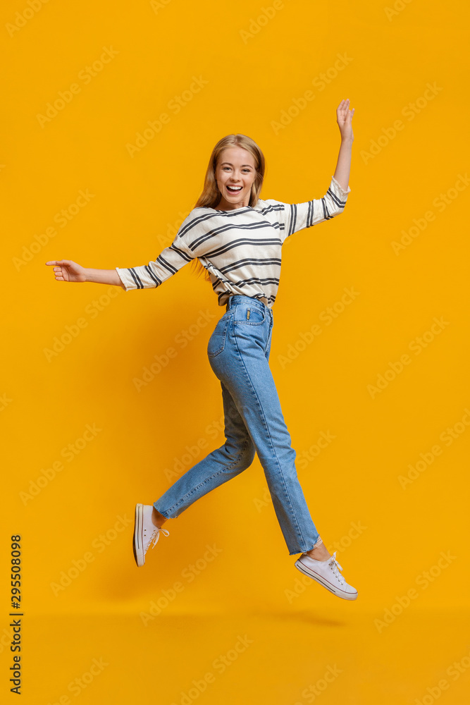Obraz premium Funny teen girl walking on air, jumping over orange background
