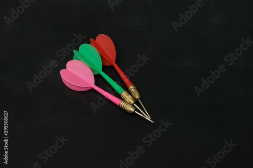 pink, green​ and​ red​ darts isolated​ on​ black​ background.