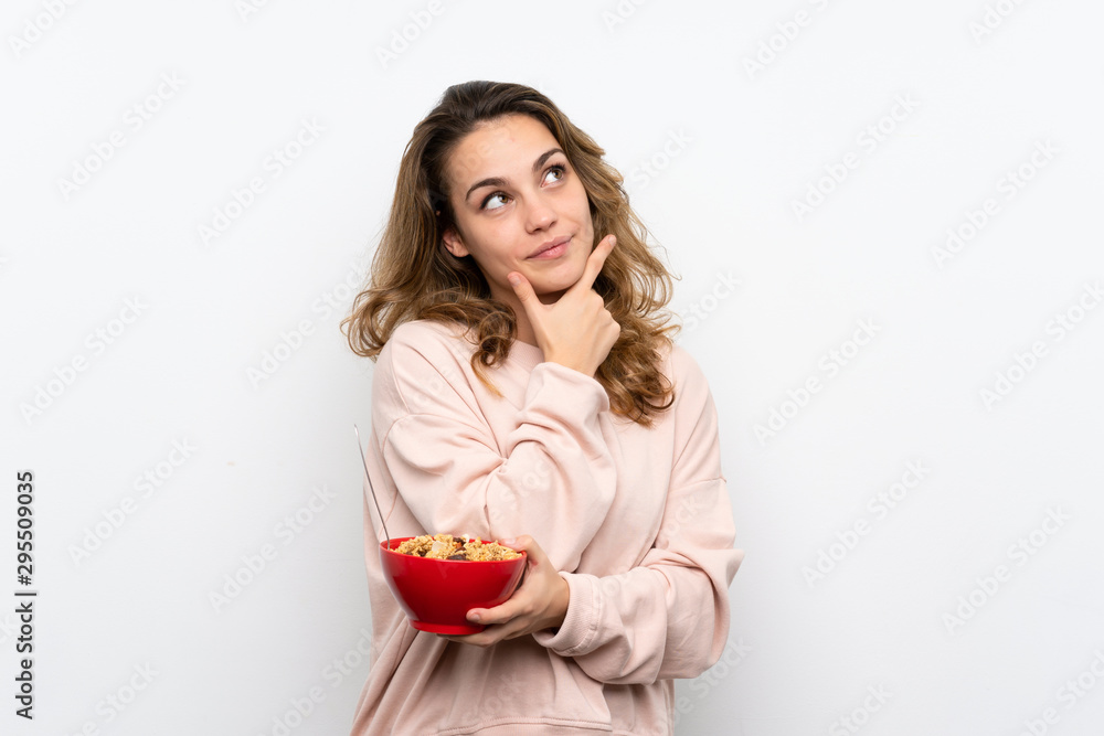Young blonde woman holding a bowl of cereals and thinking Young blonde woman holding a bowl of cereals and thinking