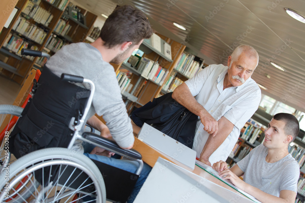 student in wheelchair in library with teacher student in wheelchair in library with teacher