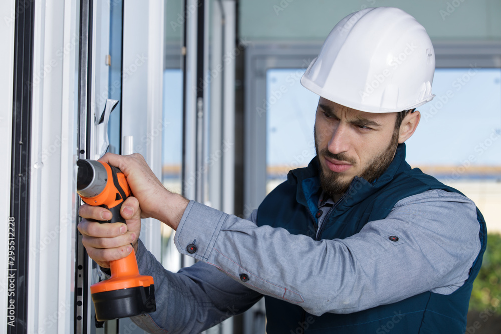 concentrated man with screwdriver tightens window