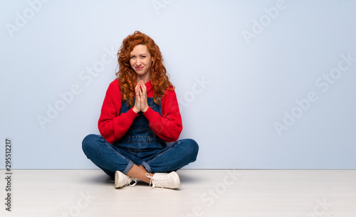 Redhead woman with overalls sitting on the floor scheming something