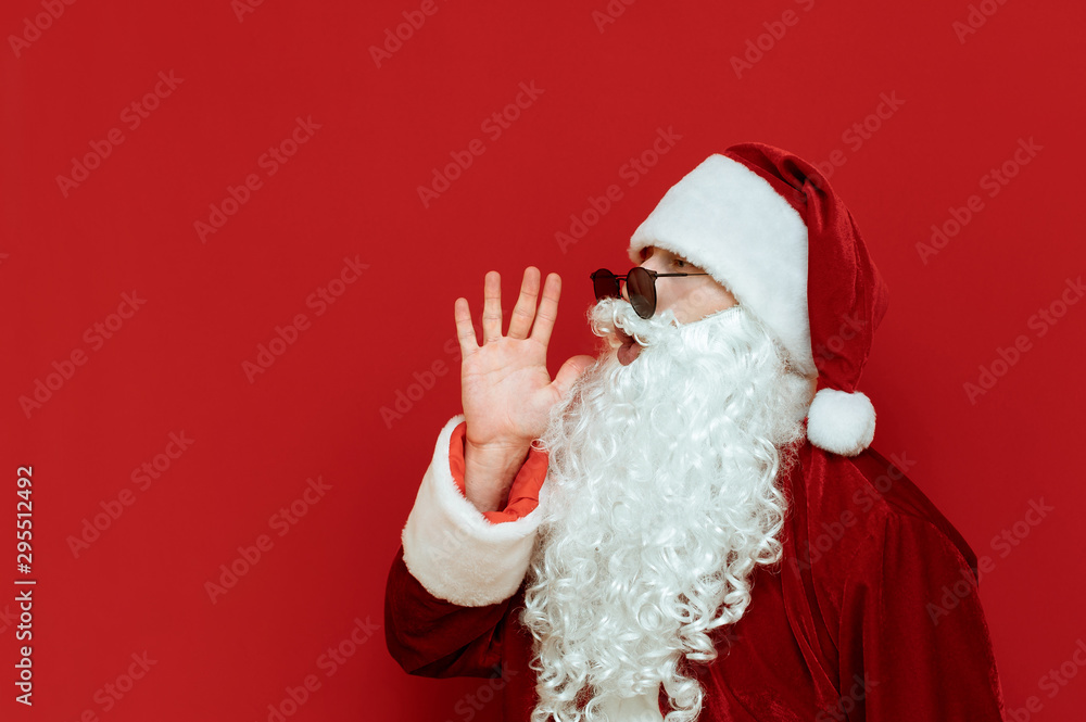 Closeup portrait of Santa yelling and looking away on red background. Santa speaks aside to the empty space. Christmas concept. Santa and place for text. X-mas Santa and Copyspace