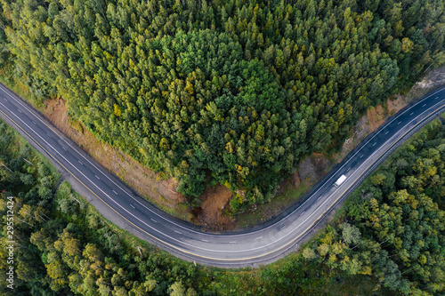 Top down aerial view of mountain road curve among green forest trees. Small cargo truck on the highway. P-258 road on the shore of Baikal Lake near Baikalsk, Buryatia, Russia