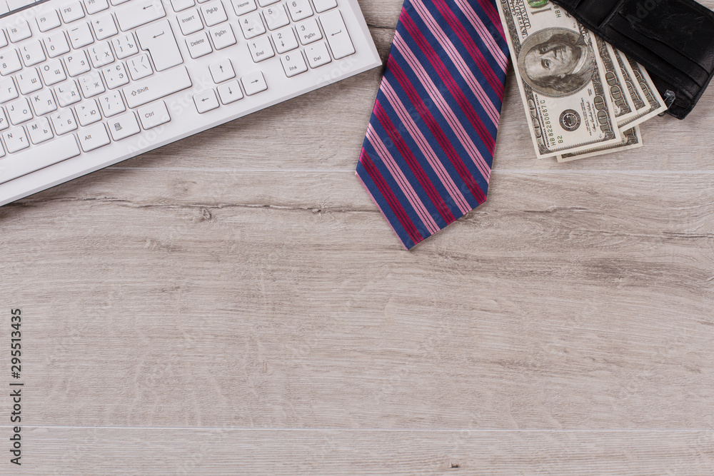 Obraz premium Keyboard on table close up. Striped tie and wallet full of money. Office worker's salary.