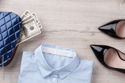 Shirt, black heels and wallet with american dollars. Stylish woman ready to work. Office concept.