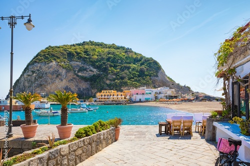 Beautiful coast of village Sant'Angelo, giant green rock in blue sea near Ischia Island, Italy. photo