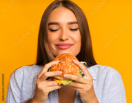 Happy Girl Eating Burger Standing, Studio Shot