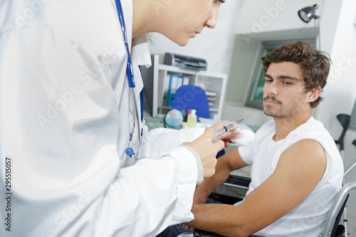 young man receiving injection from medical assistant in clinic