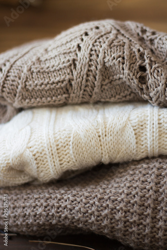 Stack of cozy knitted sweaters on a wooden table. Retro style. Warm concept. close up © Green Juli