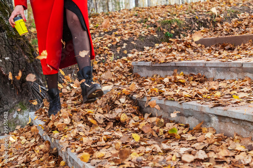 Wallpaper Mural A girl in black boots and a red coat kicks yellow and red foliage strolling in the park alone on a clear autumn day during a fall. Freshness, nature and fun. Torontodigital.ca